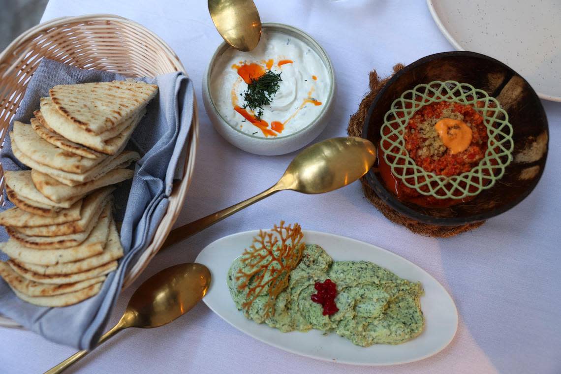Pita bread accompanies cretean feta dip, muhammara and tzatziki on a table at ZOI.