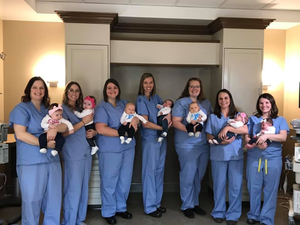 The seven Illinois nurses and obstetrician tech who were pregnant at the same time pose with their newborns.