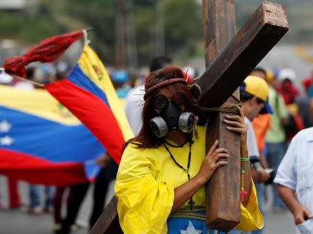 An opposition supporter carrying a cross attends a rally against Venezuela's President Nicolas Maduro in Caracas, Venezuela April 24, 2017. REUTERS/Christian Veron