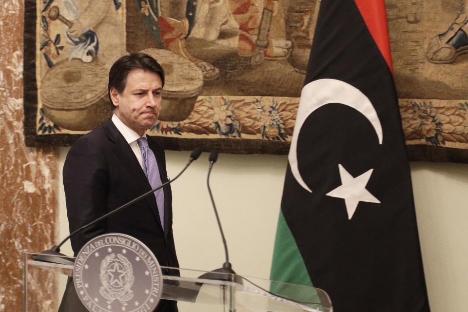 Italian Premier Giuseppe Conte walks past a Libyan flag at the end of his meeting with Libya's Prime Minister Fayez al-Sarraj at Chigi palace, in Rome, Saturday, Jan. 11, 2020. (AP Photo/Gregorio Borgia)