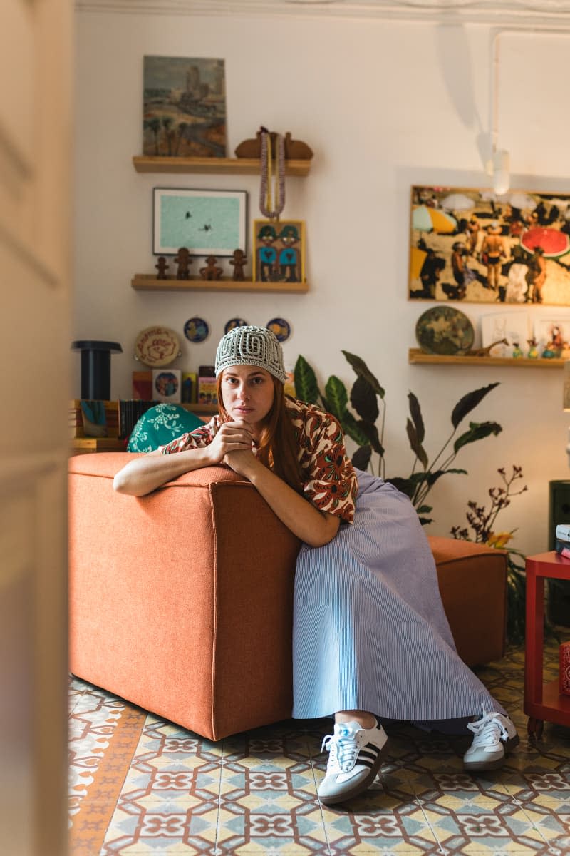 Dweller sits in orange chair in living room with colorful floor.