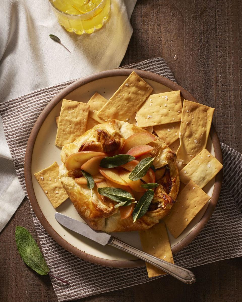 honey apple baked brie with fried sage on a plate with crackers for serving