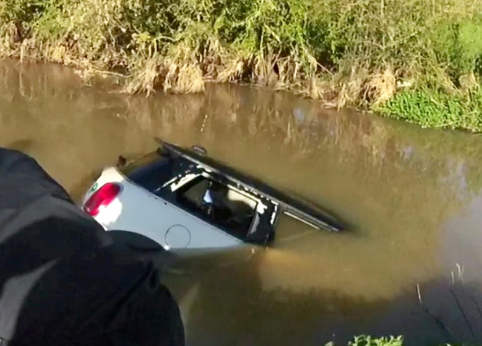 Moments after police dragged the woman from the sinking car it became completely submerged. (SWNS)