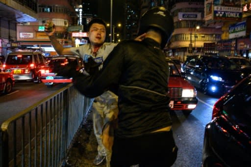 An unidentified man holds a brick as he fights with a group of people after a flashmob rally in Hong Kong, a day after the city's leader outlawed face coverings at protests