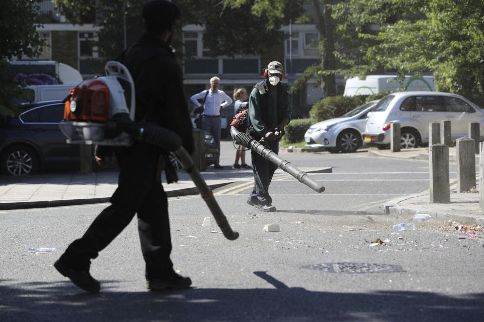 Volunteers clean up the streets following overnight violent confrontations with police, in the Brixton area of London, Thursday June 25, 2020. Authorities have reported some fifteen officers were injured and four people were arrested following the incident. (Jonathan Brady/PA via AP)