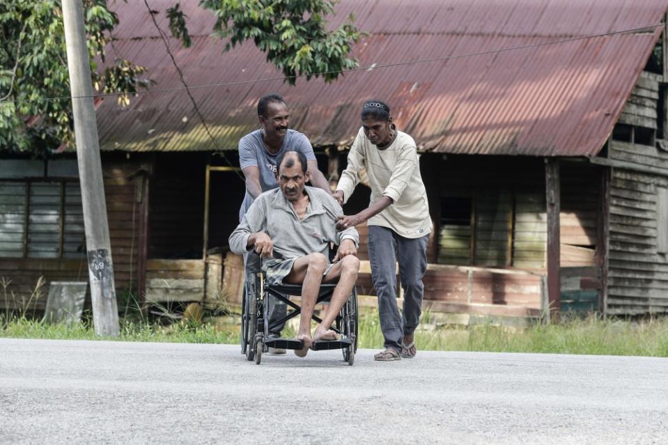 Manimala (right) taking Ali Mohammed for a walk in his wheelchair. — Picture by Sayuti Zainudin