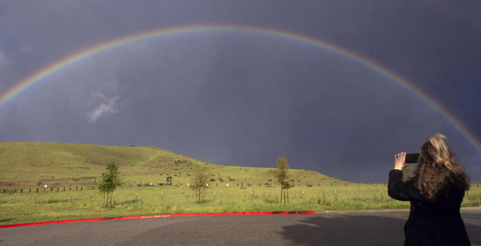 Brittany Johnson, of Irvine, stops to take a picture of a full rainbow after grocery shopping in Irvine, Calif., Sunday, March 31, 2024. (Mindy Schauer/The Orange County Register via AP)