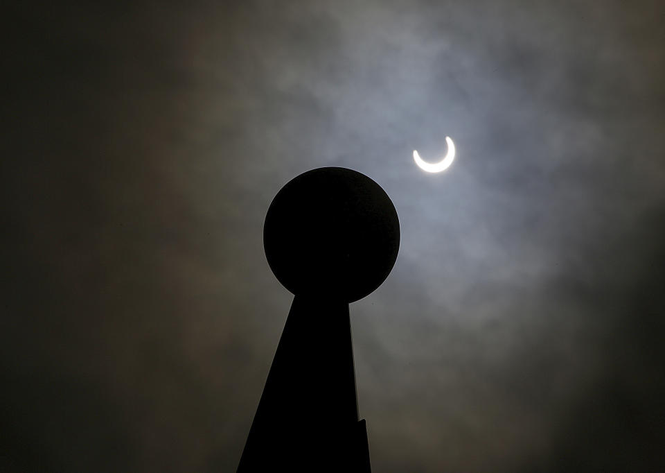 The sun, partially blocked clouds, is seen next to the top of a sundial during a “ring of fire” eclipse of the sun at the University of Texas Rio Grande Valley in Edinburg, Texas, Saturday, Oct. 14, 2023. (Joel Martinez/The Monitor via AP)