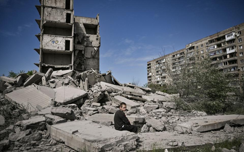 A young boy sits in front of a damaged building after a strike in Kramatorsk in the eastern Ukranian region of Donba - ARIS MESSINIS /AFP