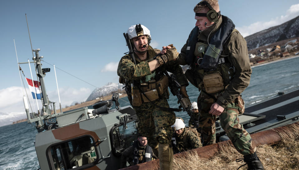 In this image provided by the North Atlantic Treaty Organization, a Dutch amphibious reconnaissance marine helps a U.S. Marine off of a Dutch landing craft near Sandstrand, Norway, March 21, 2022, during the Exercise Cold Response 22. (NATO via AP)