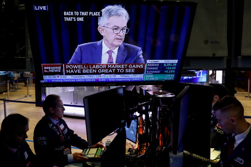 FILE PHOTO: Traders work as a screen shows Federal Reserve Chairman Jerome Powell's news conference after the U.S. Federal Reserve interest rates announcement on the floor of the NYSE in New York