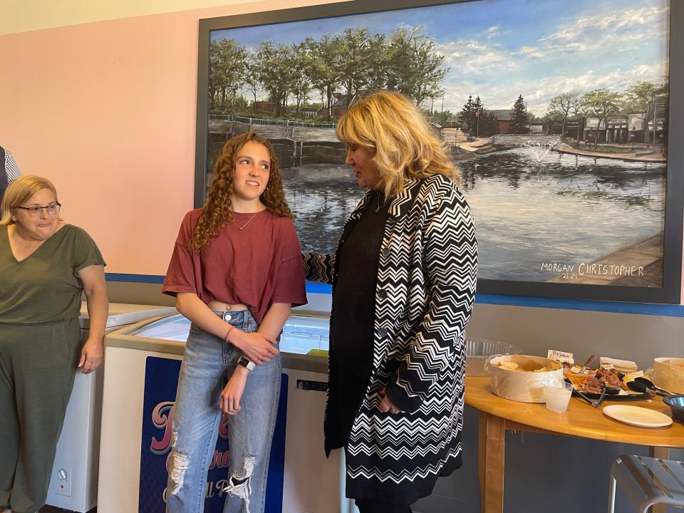 From left, Jackie's Custard Co. owner Andrea Cartier looks on as teen artist Morgan Christopher is honored by Brighton Area Chamber of Commerce president Pam McConeghy after her mural of the Brighton Mill Pond was unveiled, Thursday, April 25, 2024.