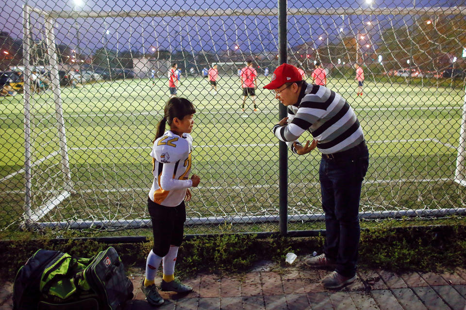 <p>Lisa Li, 9, of the Eagles listens to her father before she plays the Sharklets in their Future League American football youth league match in Beijing, May 26, 2017. (Photo: Thomas Peter/Reuters) </p>