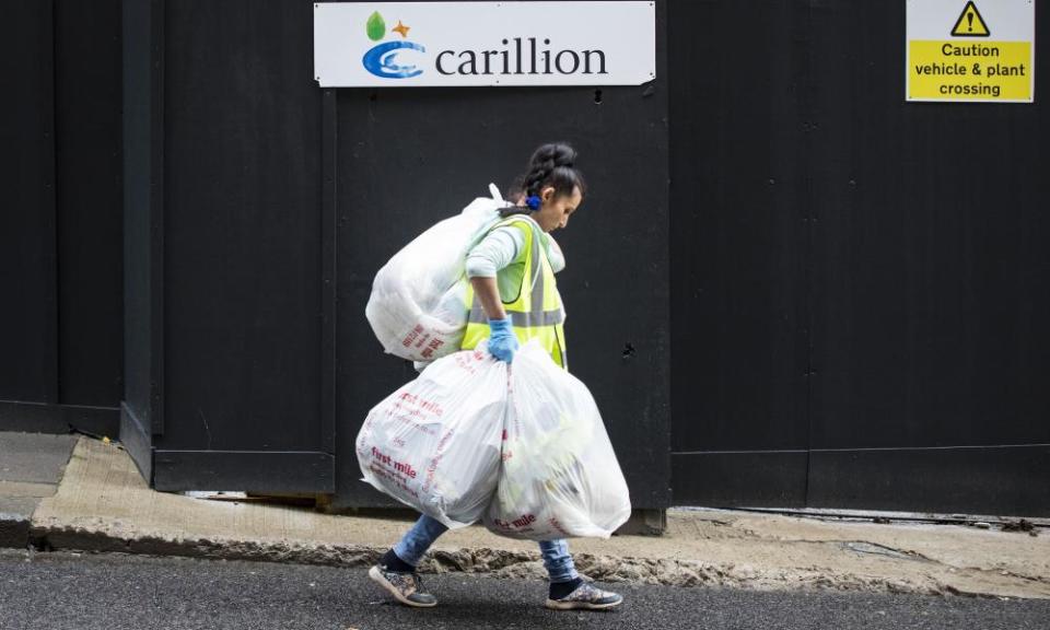 Rubbish bags are carried away from a closed Carillion construction site