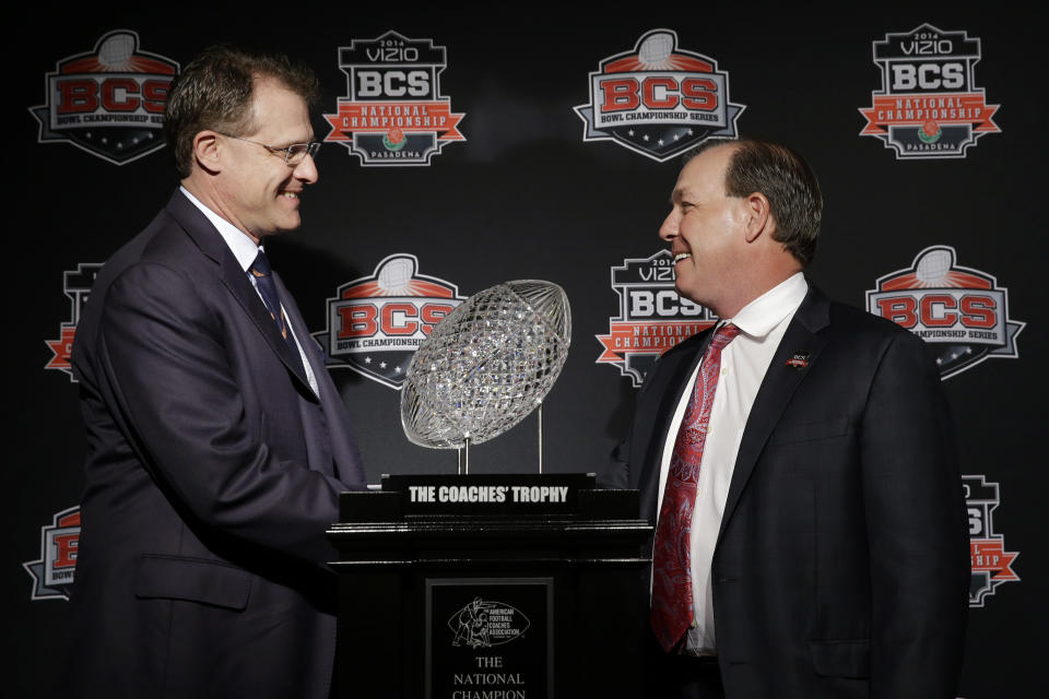 Auburn head coach Gus Malzahn, left, and Florida State head coach Jimbo Fisher shake hands in front of The Coaches' Trophy during a news conference for the NCAA BCS National Championship college football game Sunday, Jan. 5, 2014, in Newport Beach, Calif. Florida State plays Auburn on Monday, Jan. 6, 2014. (AP Photo/David J. Phillip)