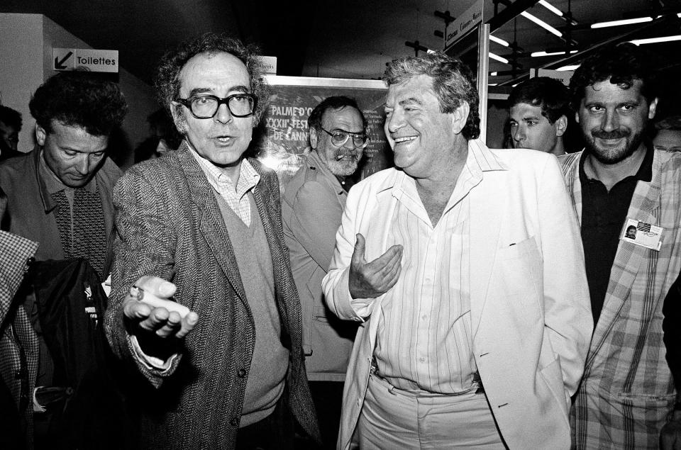 FILE - Movie director Jean-Luc Godard, left, and Israeli producer Menahem Golan, right, gesture as they speak to the press in Cannes, France, after the screening of Godard's out of competition "King Lear," produced by Cannon group, as part of the 40th Cannes Film Festival on May 17, 1987. Director Jean-Luc Godard, an icon of French New Wave film who revolutionized popular 1960s cinema, has died, according to French media. He was 91. Born into a wealthy French-Swiss family on Dec. 3, 1930, in Paris, the ingenious "enfant terrible" stood for years as one of the world's most vital and provocative directors in Europe and beyond — beginning in 1960 with his debut feature "Breathless." (AP Photo/Pierre Gleizes, File)