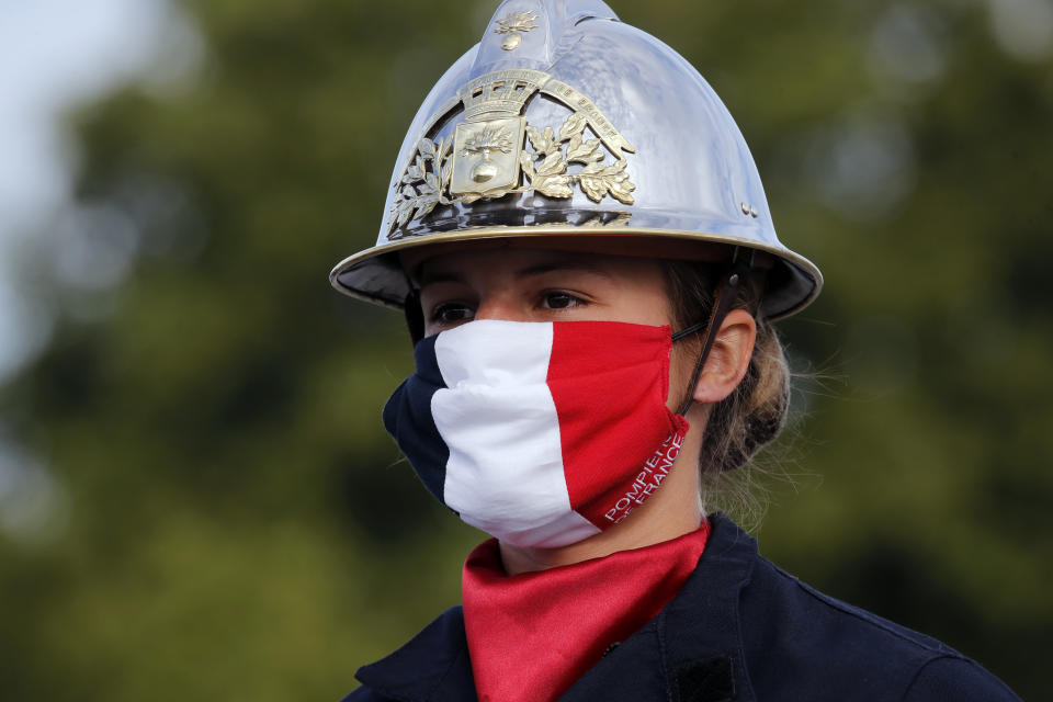 A firefighter wears a face mask with the colors of the French flag, prior to the Bastille Day parade Tuesday, July 14, 2020 on the Champs Elysees avenue in Paris. France are honoring nurses, ambulance drivers, supermarket cashiers and others on its biggest national holiday Tuesday. Bastille Day's usual grandiose military parade in Paris is being redesigned this year to celebrate heroes of the coronavirus pandemic. (AP Photo/Christophe Ena, Pool)