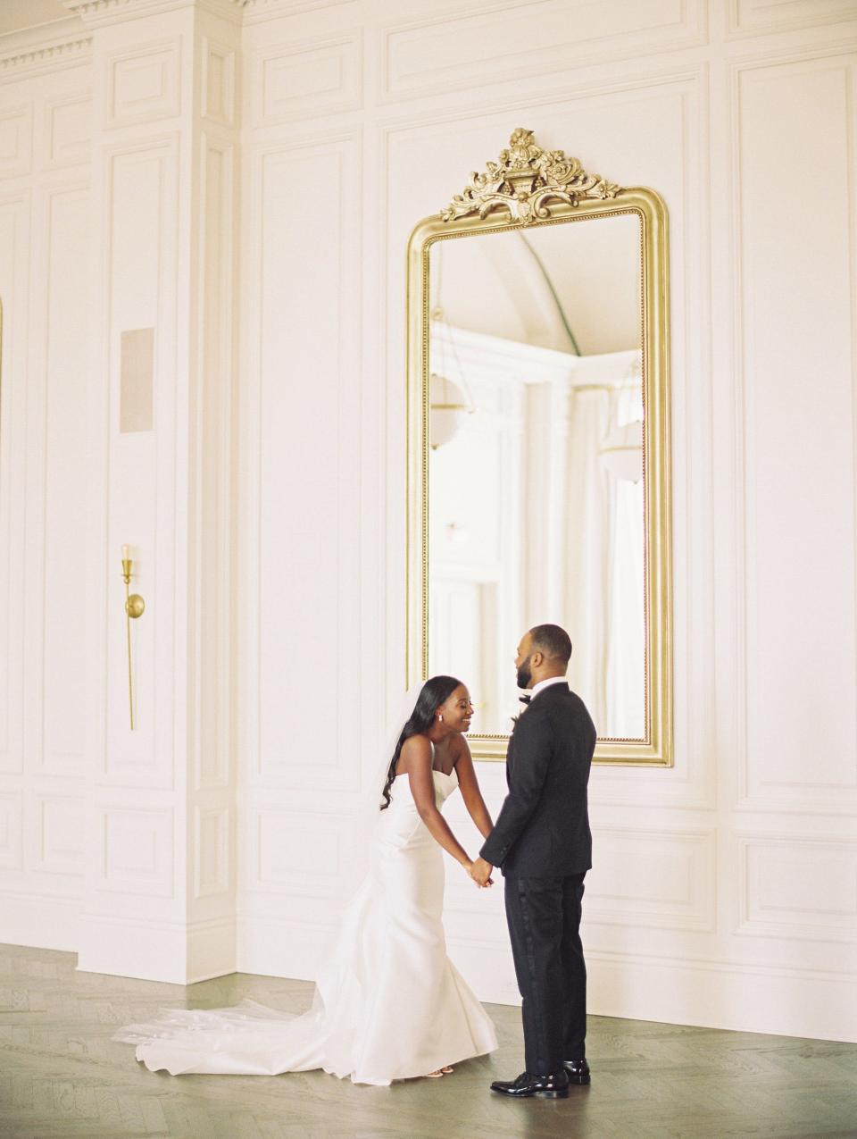 A bride and groom hold hands and laugh on their wedding day.