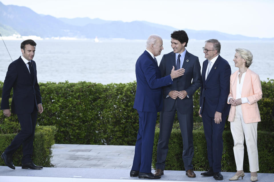 From left, France's President Emmanuel Macron arrives as US President Joe Biden speaks with Canada's Prime Minister Justin Trudeau, Australia's Prime Minister Anthony Albanese and European Commission President Ursula von der Leyen as they gather for a group photo of leaders of the G7 and invited countries during the G7 Leaders' Summit in Hiroshima, western Japan, Saturday, May 20, 2023. (Brendan Smialowski/Pool Photo via AP)