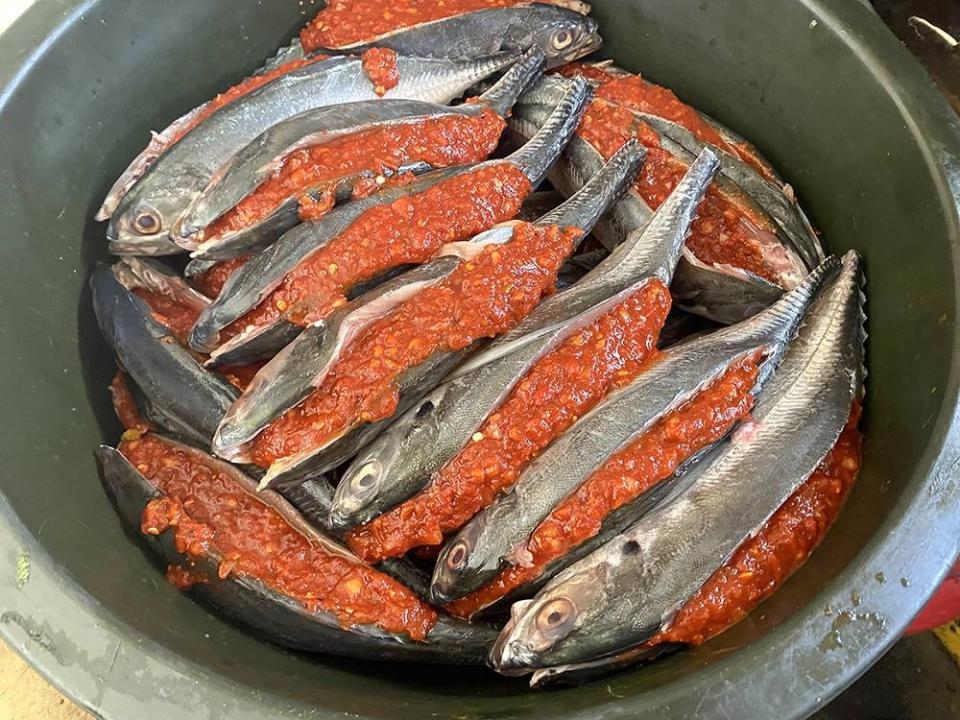 The fish is sliced and stuffed with a bright red spice paste before frying.