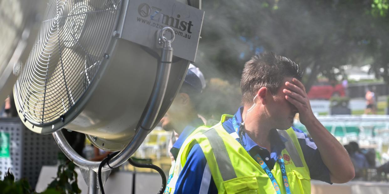 A man wipes sweat from his face in sweltering heat.