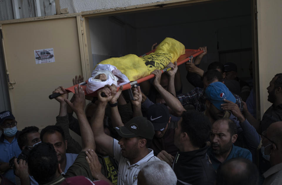 Palestinian mourners carry the body of 11-year-old Hussain Hamad, who was killed by an explosion during the ongoing conflict between Israel and Hamas, out of the morgue during his funeral in Beit Hanoun, northern Gaza Strip, Tuesday, May 11, 2021. (AP Photo/Khalil Hamra)