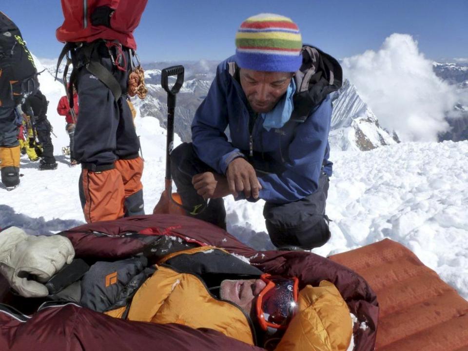 In this picture taken Sunday, Sept. 23, 2012 and released by Alpine Ascents International, an unidentified rescuer speaks to an unidentified survivor in the debris field of an avalanche on Mount Manaslu in northern Nepal. Rescue helicopters flew over the high slopes of the northern Nepal peak again Monday to search for climbers lost in an avalanche that killed at least nine mountaineers and injured others. Many of the climbers were French, German and Italian. (AP Photo/Garrett Madison, Alpine Ascents International)