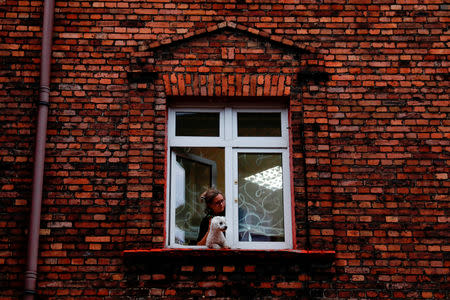 A woman with a dog look out from the window in Nikiszowiec district in Katowice, Poland, October 17, 2018. REUTERS/Kacper Pempel