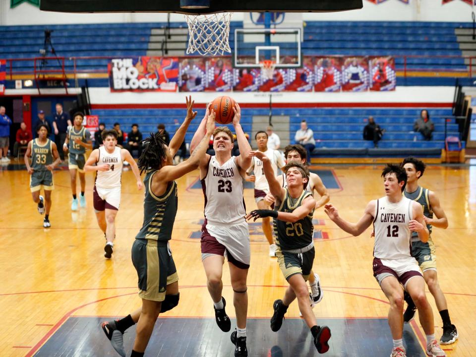 Mishawaka senior Brady Fisher (23) attacks the rim while being defended by two Warren Central players during a boys basketball game Saturday, Dec. 23, 2023, at Kokomo High School.