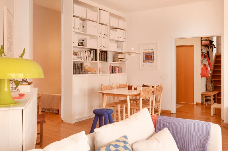 White dining room with floor-to-ceiling white bookshelves, light wood table and chairs