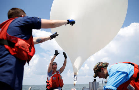 College of Charleston professor Dr. Cassandra Runyon (Center) releases a balloon during a test launch for the Space Grant Ballooning Project in preparations for Monday's solar eclipse on board a US Coast Guard response boat at sea near Charleston, South Carolina, U.S. August 17, 2017. Location coordinates for this image are 32º41' 975" N 79º44'195" W. REUTERS/Randall Hill