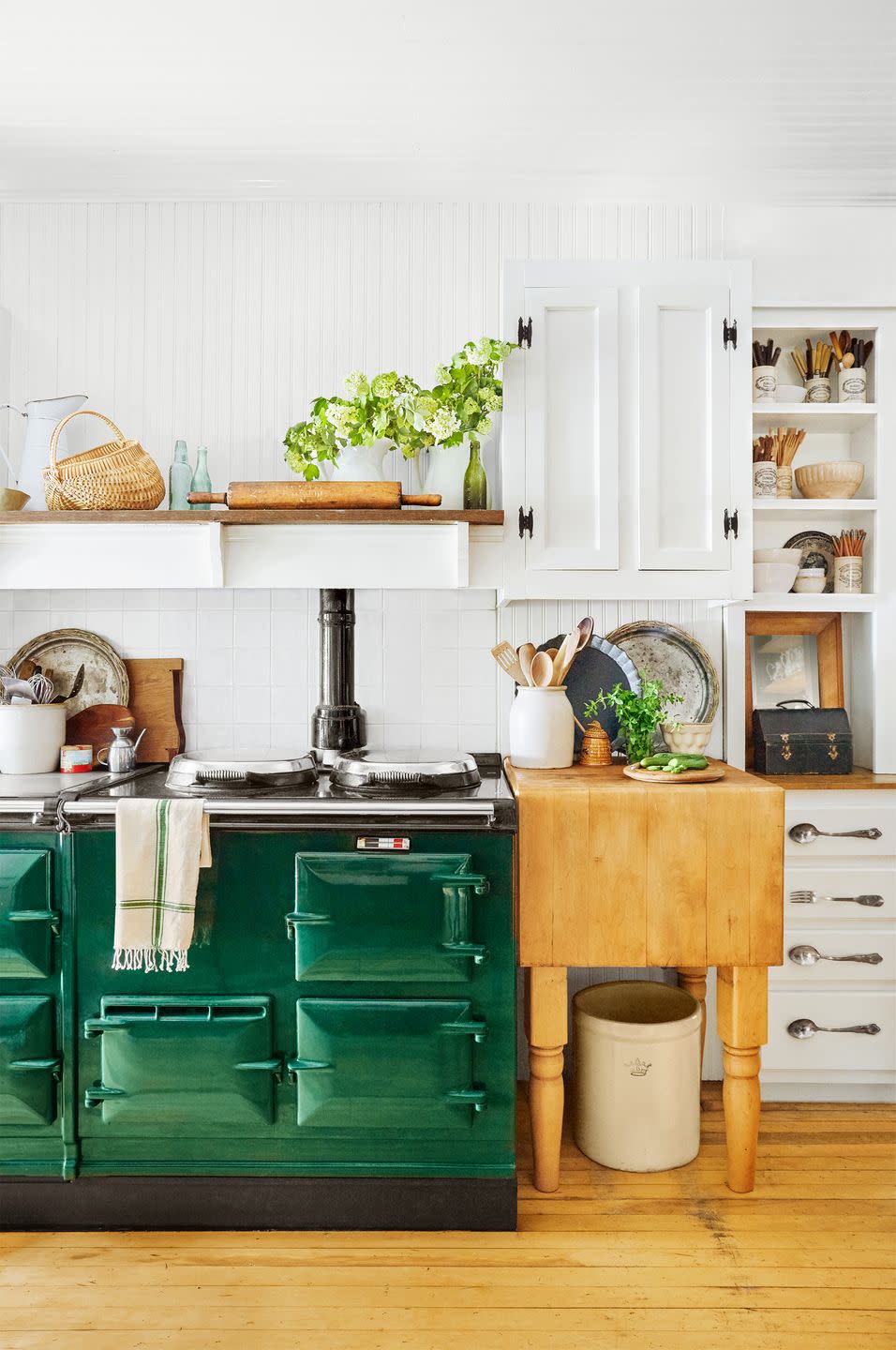 a farmhouse kitchen that has a vintage dark green stove as a focal point