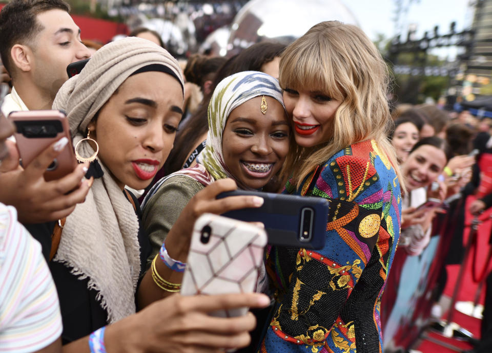 FILE - Taylor Swift, right, takes selfies with fans as she arrives at the MTV Video Music Awards at the Prudential Center on Monday, Aug. 26, 2019, in Newark, N.J. Taylor Swift and Travis Kelce have remained mum about their status since the pop superstar began attending the Kansas City Chiefs tight end's football games. (Photo by Charles Sykes/Invision/AP, File)