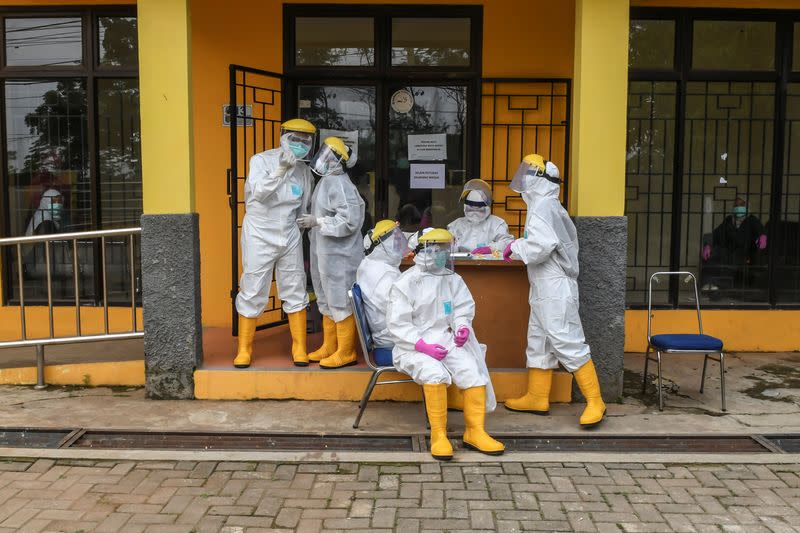 Medical officers prepare before administering a test for coronavirus disease (COVID-19) to a patient at a drive-through testing site in a parking lot at the regional lab in Depok