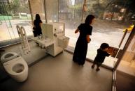 A mother and her son check out the transparent public toilet that becomes opaque when occupied, designed by Japanese architect Shigeru Ban, at Yoyogi Fukamachi Mini Park in Tokyo