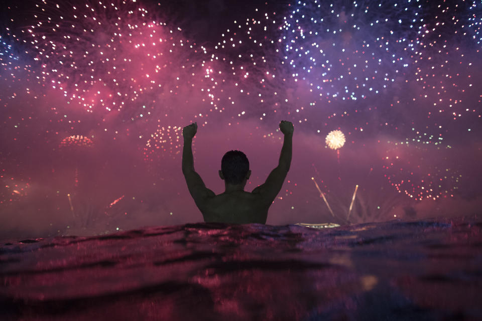 A man watches the fireworks exploding over Copacabana Beach during the New Year's celebrations in Rio de Janeiro, Brazil, Tuesday, Jan. 1, 2019. (AP Photo/Leo Correa)