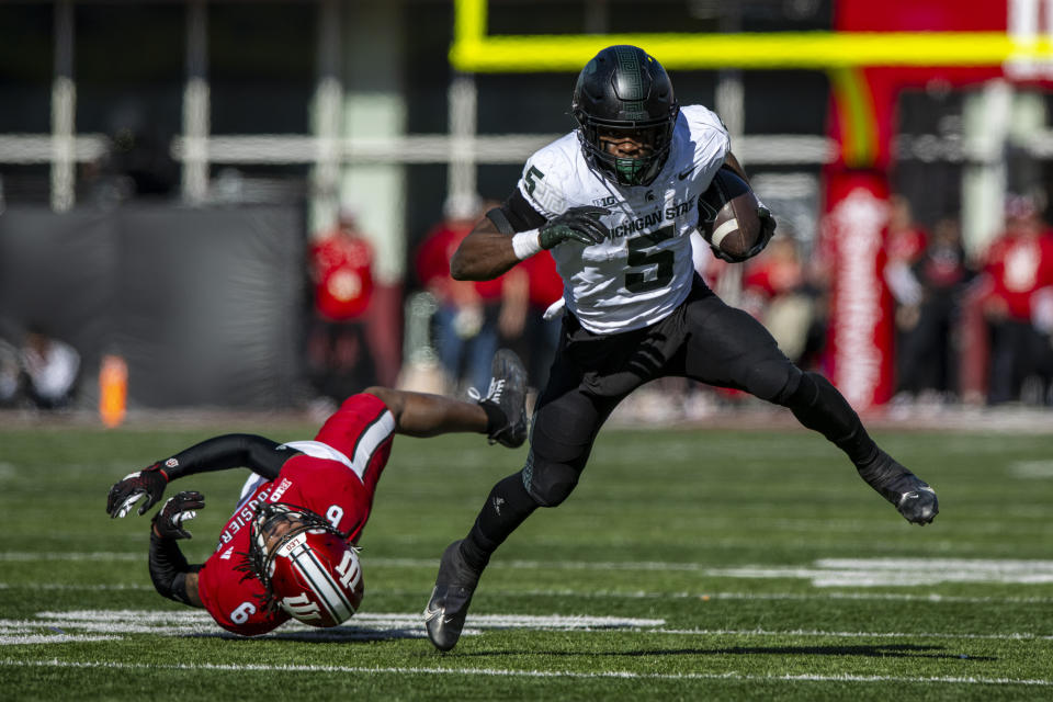 Michigan State running back Nathan Carter (5) slips out of a tackle effort of Indiana defensive back Phillip Dunnam (6) during an NCAA college football game, Saturday, Nov. 18, 2023, in Bloomington, Ind. (AP Photo/Doug McSchooler)