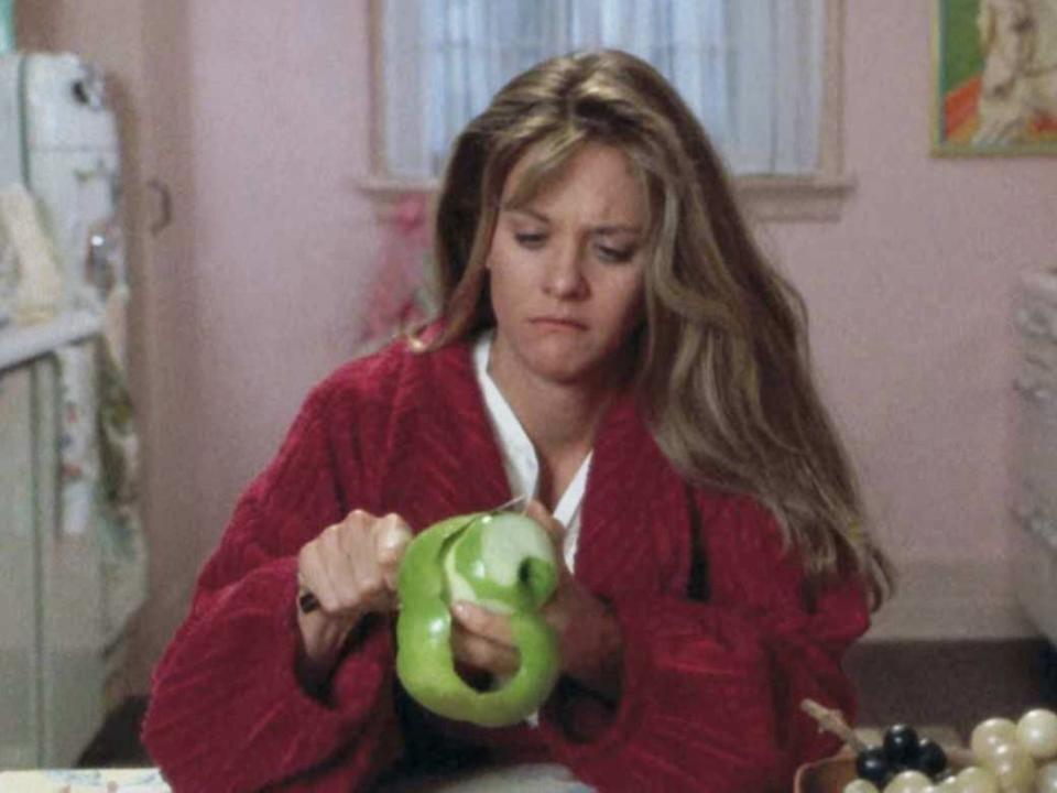 Meg Ryan peeling an apple with a knife.