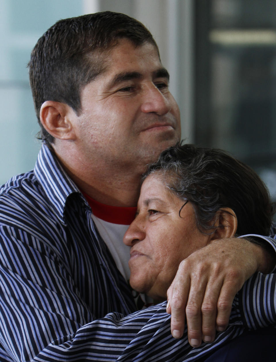 Sea survivor Jose Salvador Alvarenga, center, embraces his mother Maria Julia, after they arrive at the airport in Mexico City, Friday, March 14, 2014. The Salvadoran fisherman, who was lost at sea for 13 months, traveled from El Salvador with his parents to Mexico to fulfill a promise he made to his dead sea mate, Mexican Ezequiel Cordoba. Alvarenga said Cordoba died a month into their ordeal because he couldn't stomach the diet of raw fish, turtles and birds. (AP Photo/Marco Ugarte)