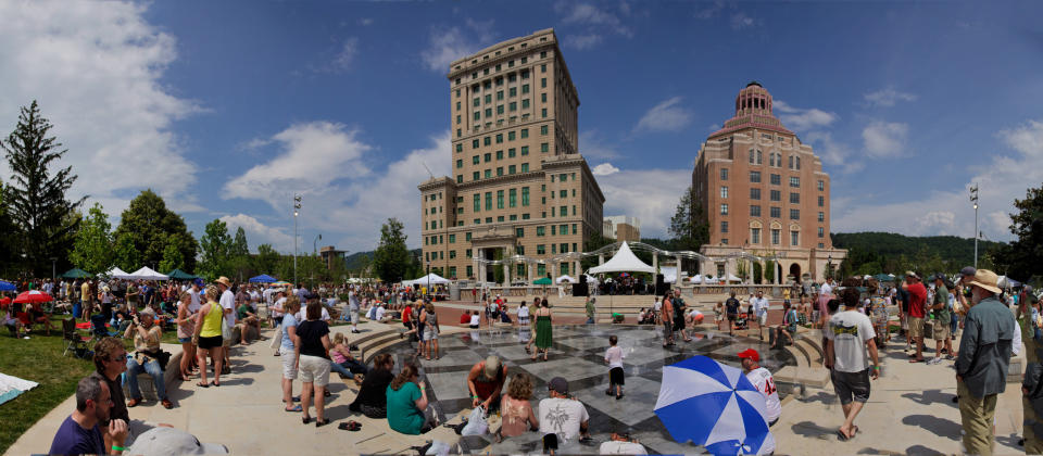 his undated image provided by Explore Asheville shows people gathering at Pack Square Park in Asheville, N.C., near the county courthouse, left, and City Hall on the right. The park is a popular place to stroll or hang out, with live music events on some summer Saturdays and an interactive water fountain. (AP Photo/Explore Asheville)