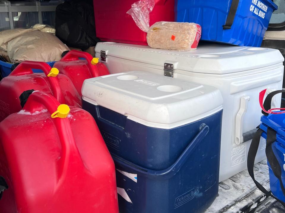A bed of a truck loaded with coolers and plastic boxes