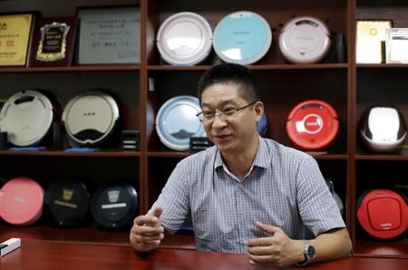 Terry Wu, deputy general manager of Matsutek, speaks next to robot vacuum cleaners on display during an interview in Shenzhen