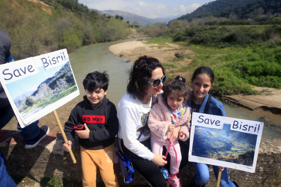 A Lebanese family holds placards during a protest against the Bisri dam project, in the Bisri Valley, 58 kilometers (36 miles) southeast of Beirut, Lebanon, Sunday, March. 10, 2019. Its expansive lands of pine, citrus trees and ancient ruins are about to turn into a controversial mega dam funded by the World Bank. For years now, activists and locals have voiced their opposition to what they describe as not only "an environmental crime," but also a project that mirrors Lebanon's governance crisis. (AP Photo/Mohammed Zaatari)