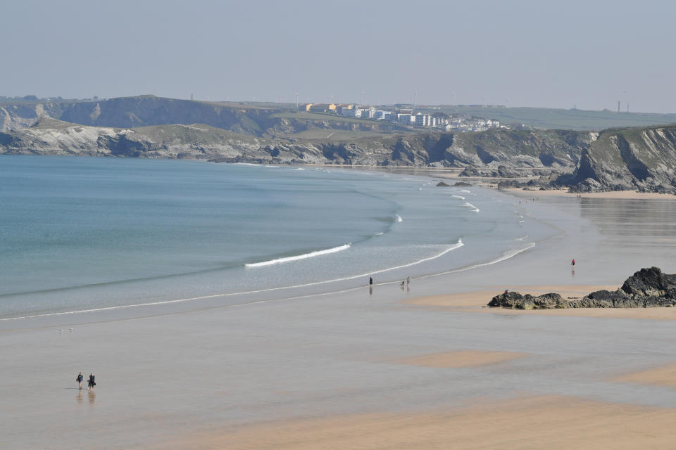 People walk on the Tolcarne beach in Newquay on the north coast of Cornwall, as the UK continues in lockdown to help curb the spread of the coronavirus.