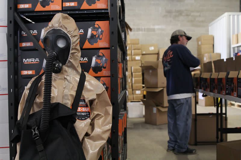 Employee Ted McLaughlin packs up orders for the CM-6M tactical gas mask near a gas mask and hazmat suit for children in the warehouse of Mira Safety in Austin