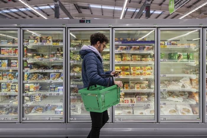 Man shopping in a supermarket while on a budget, looking for low prices due to inflation