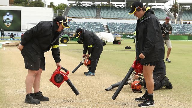 Groundsmen desperately try to dry the pitch. Image: Getty