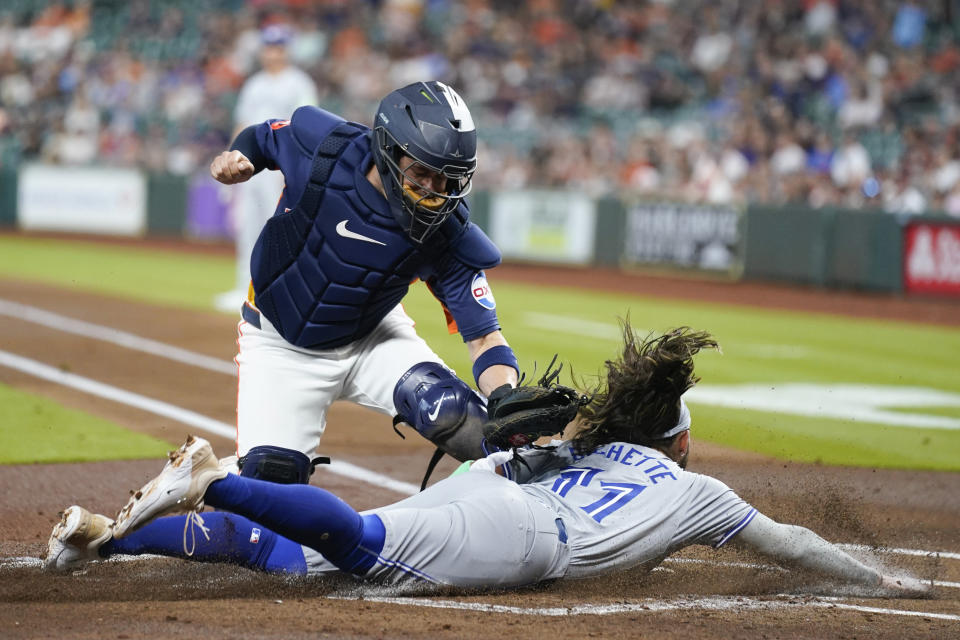 Toronto Blue Jays' Bo Bichette, bottom, is tagged out at home by Houston Astros catcher Victor Caratini during the first inning of a baseball game Tuesday, April 2, 2024, in Houston. (AP Photo/Eric Christian Smith)