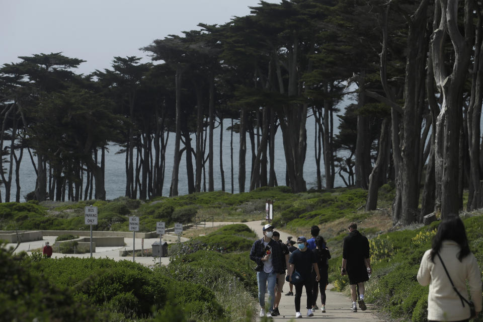 FILE - In this April 24, 2020, file photo people wear masks amid the coronavirus pandemic while walking on a path at Land's End in San Francisco. Lawmakers have reached bipartisan agreement on an election-year deal to double spending on a popular conservation program and devote nearly $2 billion a year to improve and maintain national parks. (AP Photo/Jeff Chiu, File)