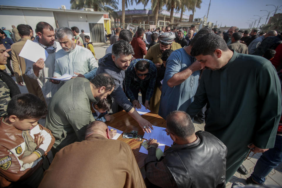 Supporters of the Shiite cleric Muqtada al-Sadr sign a pledge to stand against homosexuality or LGBTQ, outside a mosque in Kufa, Iraq, Friday, Dec. 2, 2022. Al-Sadr who announced his withdrawal from politics four months ago has broken a period of relative silence to launch an anti-LGBTQ campaign. (AP Photo/Anmar Khalil)